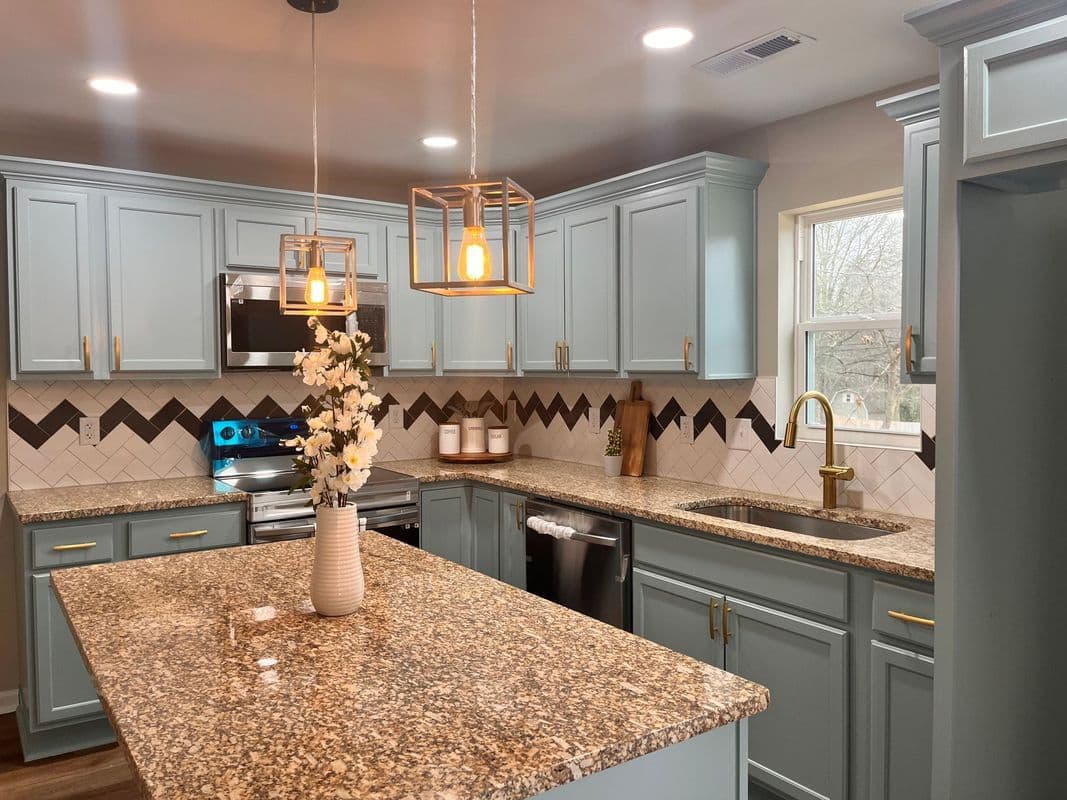 Modern kitchen with blue cabinets, granite countertops, and stylish pendant lighting.