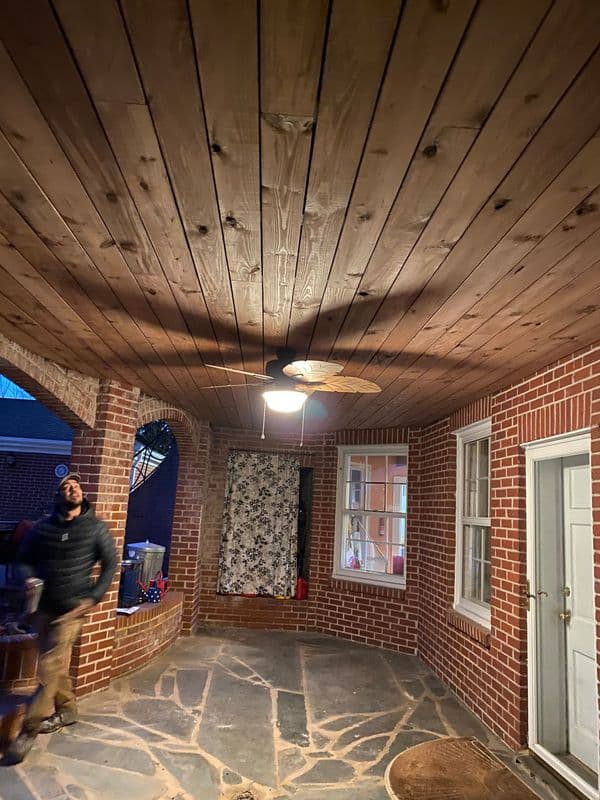 Man walking in a spacious outdoor patio with wooden ceiling and stone flooring.