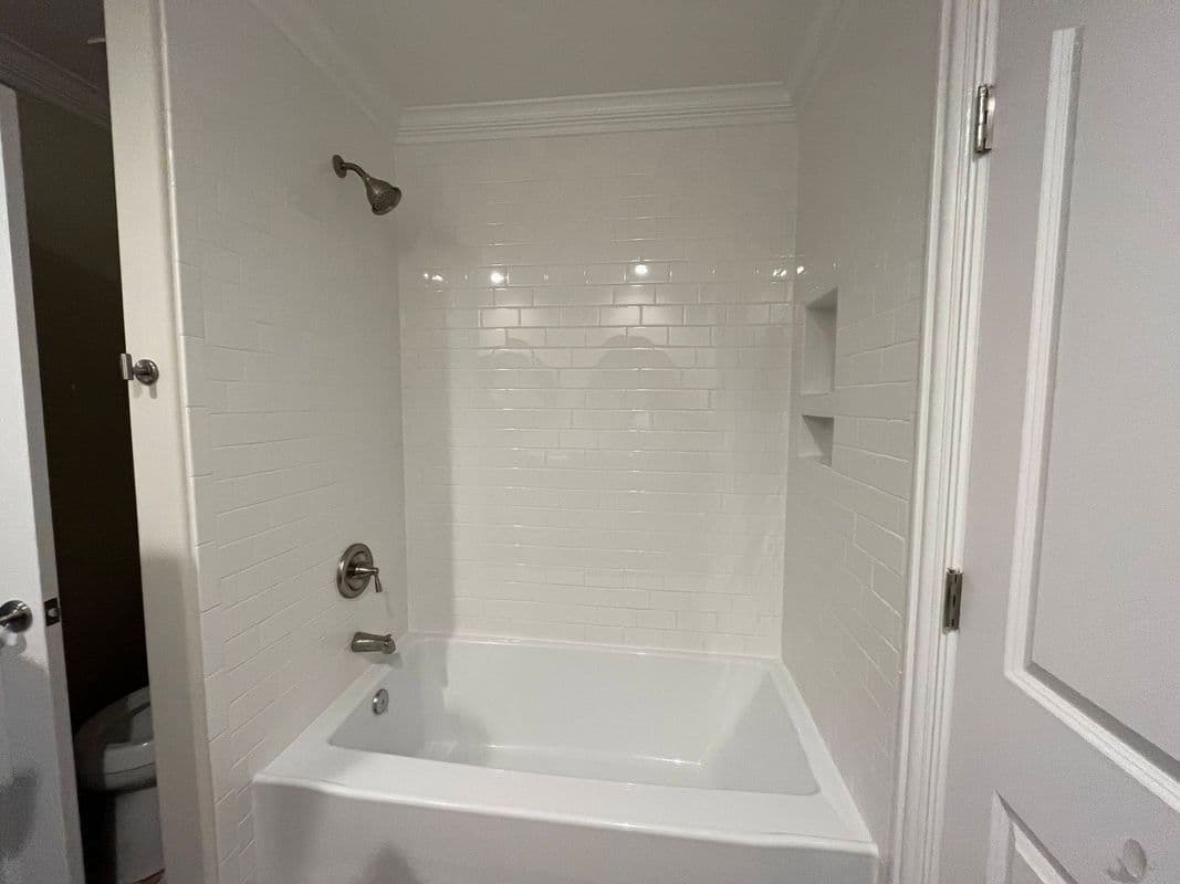Modern bathroom featuring a white tiled shower and bathtub with silver fixtures.