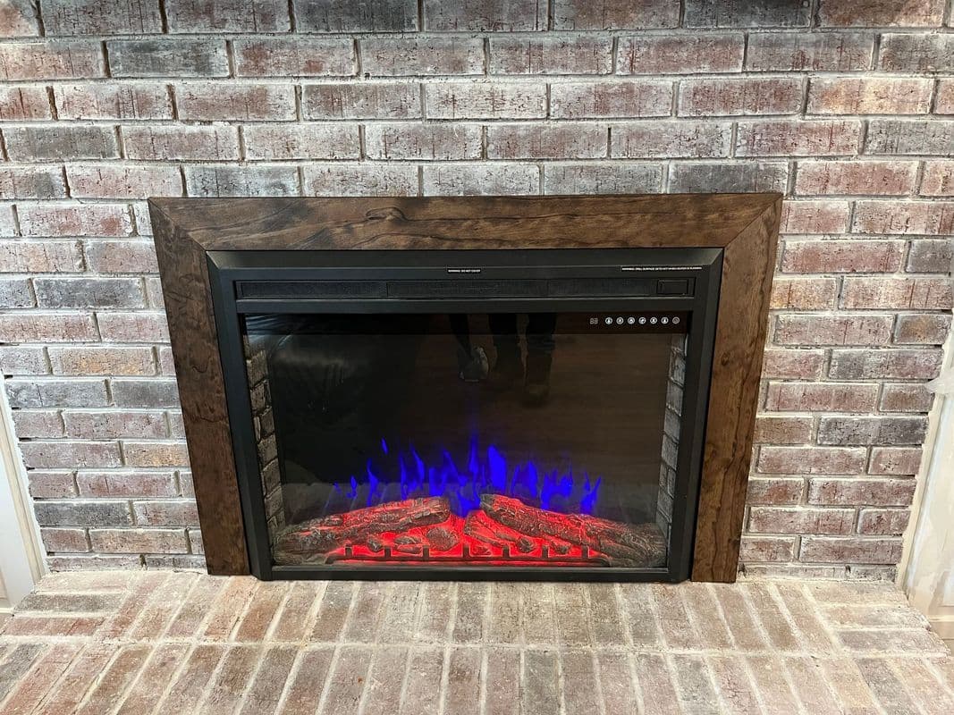 Modern electric fireplace with glowing blue and red flames, framed by a rustic brick wall.