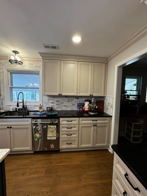 Modern kitchen featuring gray cabinets, black countertops, stainless steel appliances, and natural light.