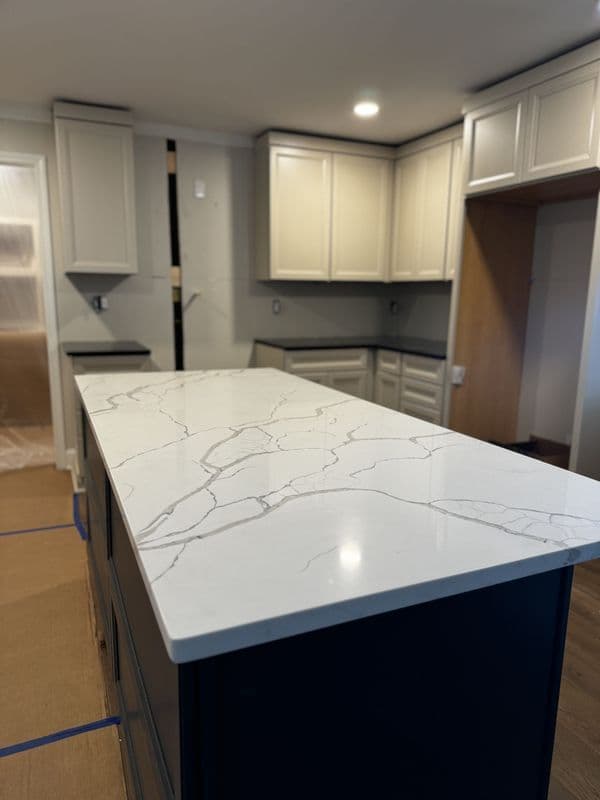 Modern kitchen with quartz countertop and light gray cabinets, featuring a spacious island.