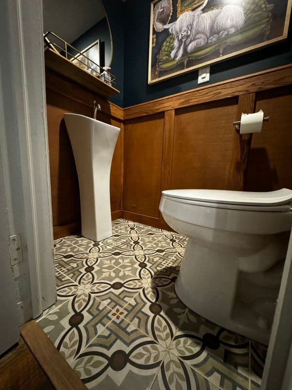 Modern bathroom design featuring a unique pedestal sink, patterned tile, and wooden accents.