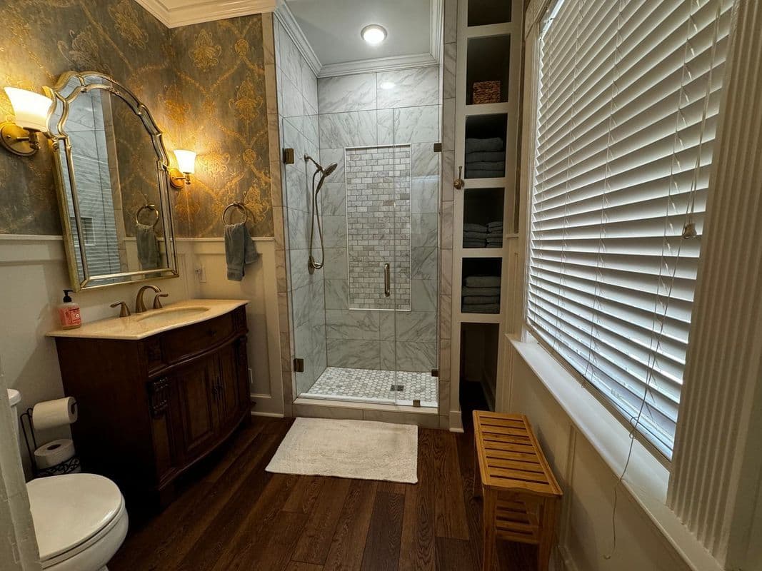 Elegant bathroom with shower, dark wood vanity, marble accents, and modern decor.