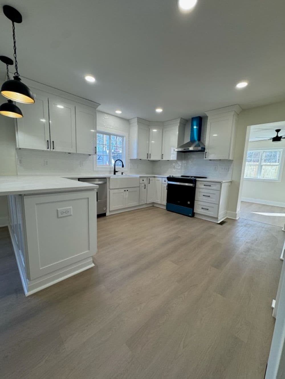 Modern kitchen with white cabinets, stainless steel appliances, and wood-look flooring.