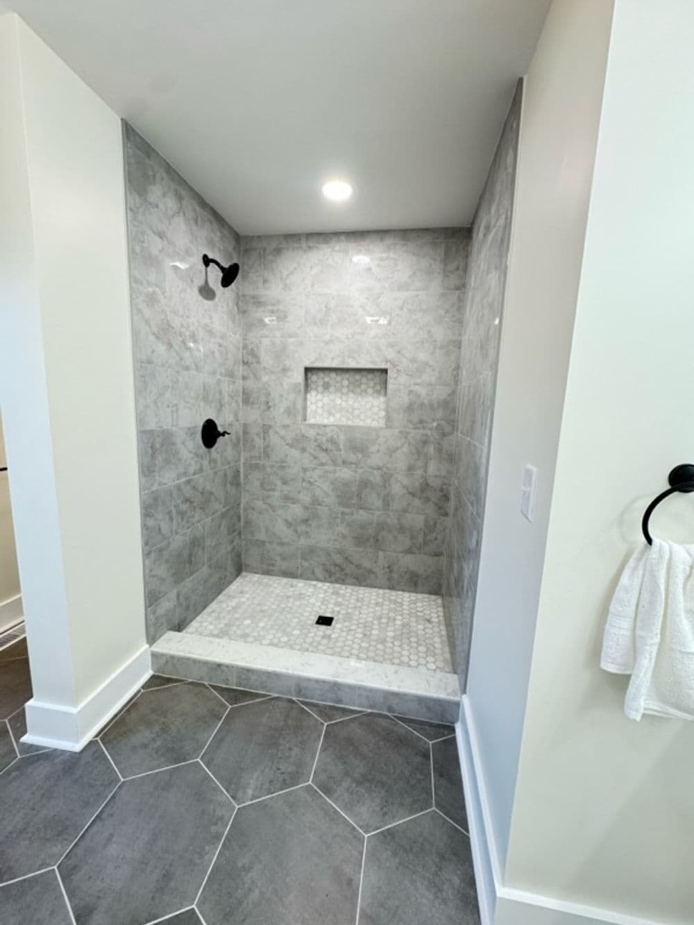 Modern bathroom shower with gray tile, elegant fixtures, and spacious design.