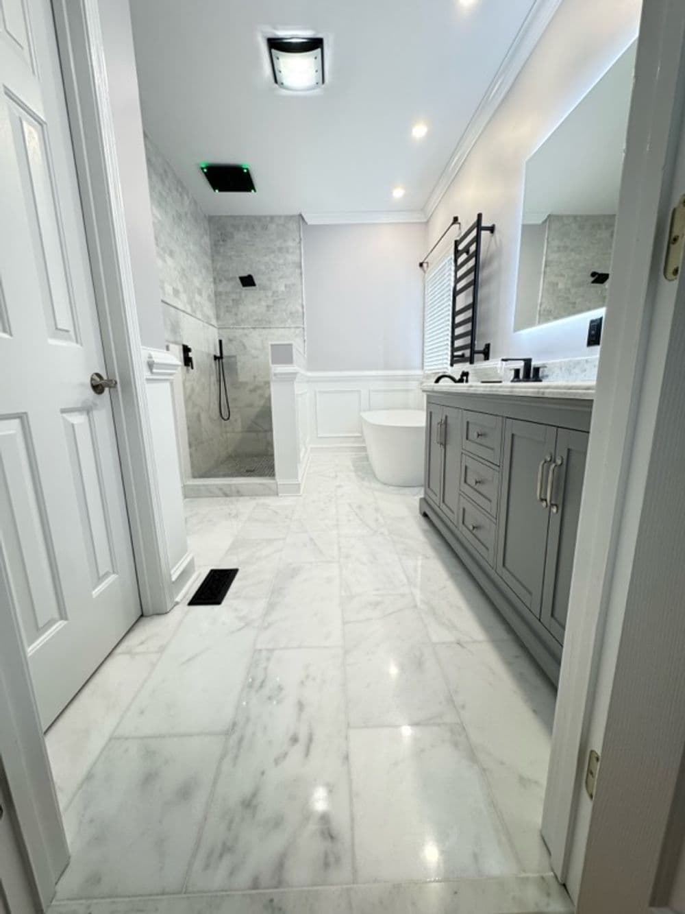 Modern bathroom with marble flooring, sleek gray cabinetry, and contemporary shower design.