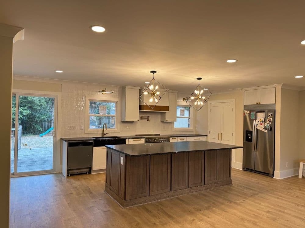 Modern kitchen with wood accents, island, and stylish light fixtures, featuring open layout.